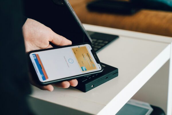Person holding a smartphone over a card reader for contactless payment representing digital banking