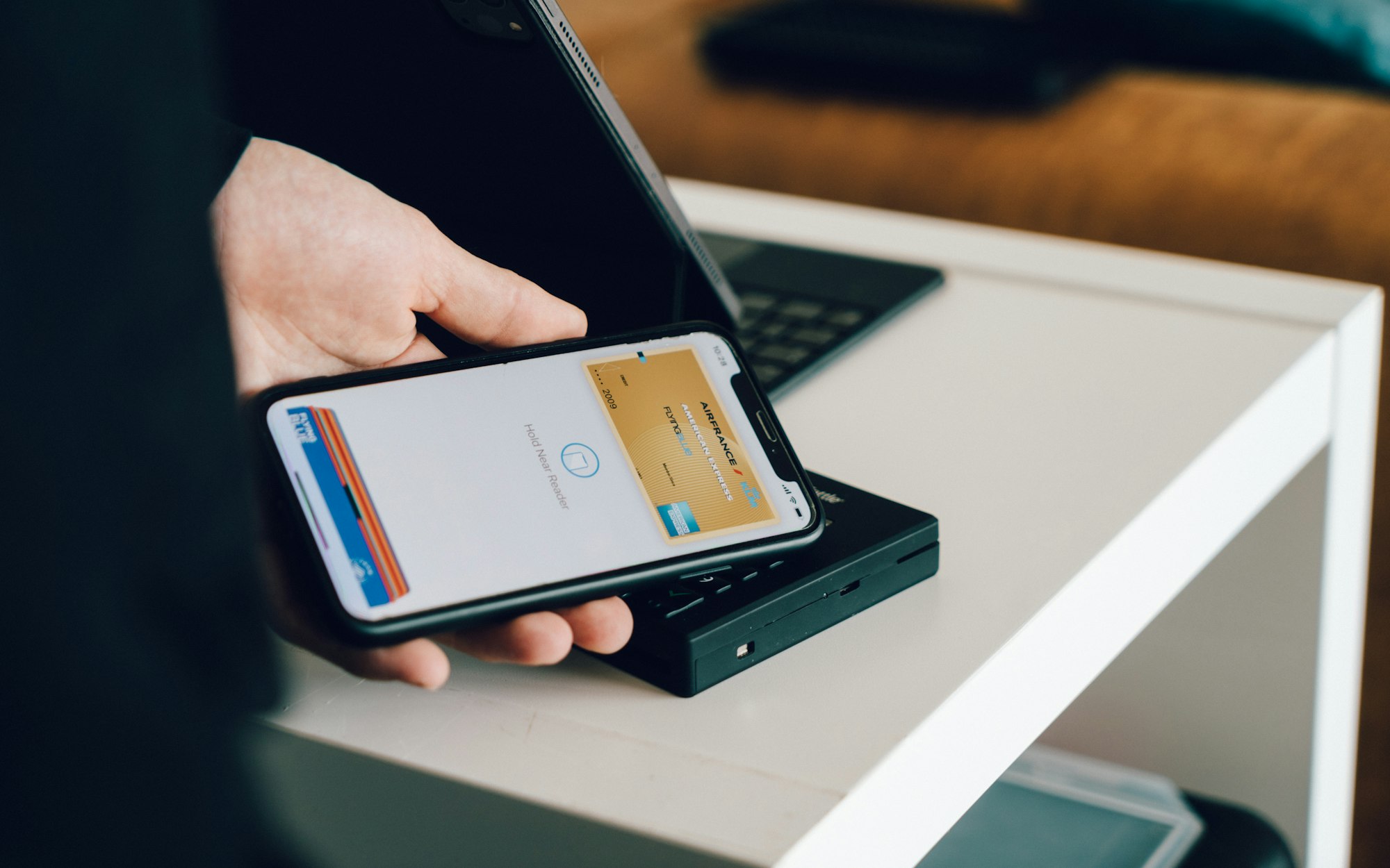 Person holding a smartphone over a card reader for contactless payment representing digital banking